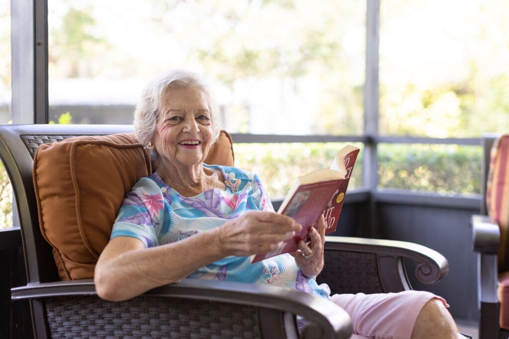 Resident of East Ridge at Cutler Bay reading a book on her porch