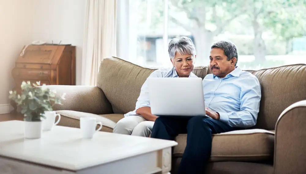 a senior couple browsing on their laptop in the living room