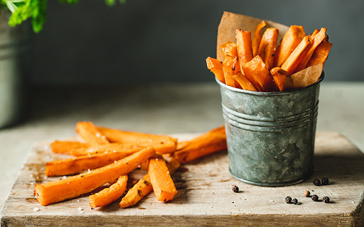 patatas fritas de boniato al horno derramándose sobre una mesa