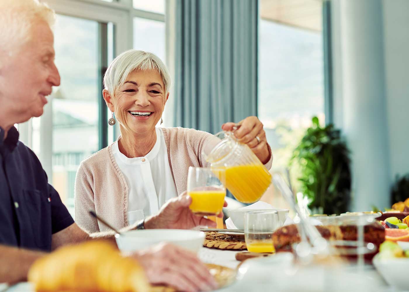 senior woman pouring a glass of orange juice for her husband