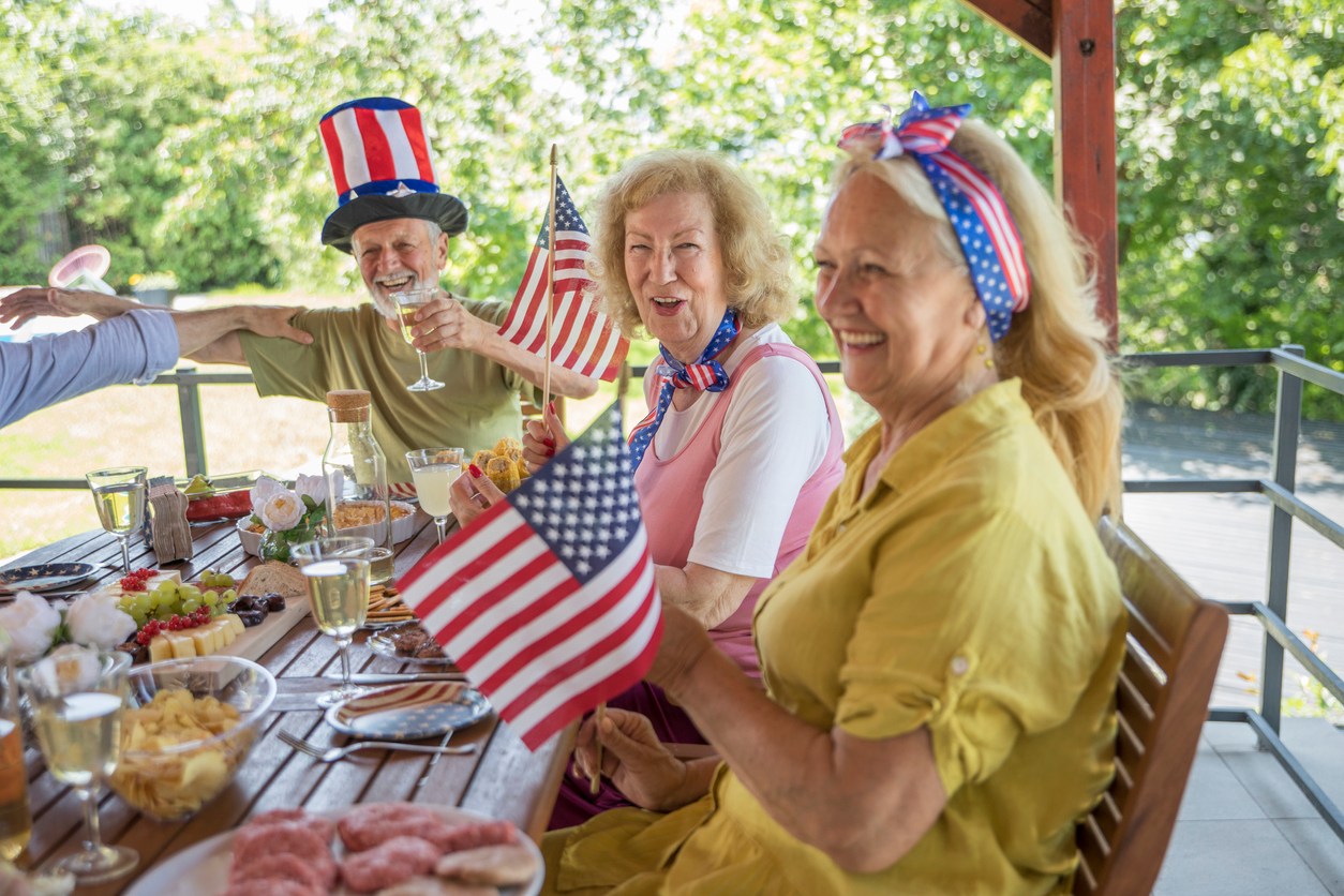 Seniors dressed in patriotic attire and waving American Flags at an outdoor event
